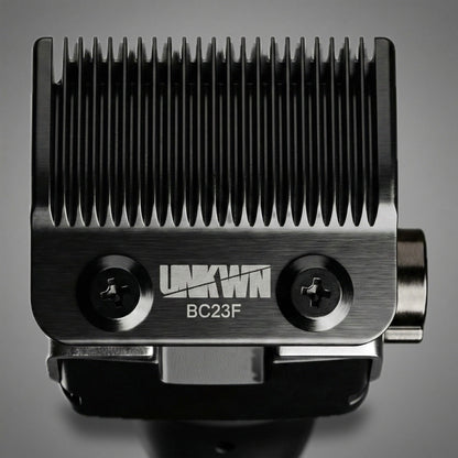 Close-up of the BC23F fade blade mounted on the UNKWN Vortex Cyclone Clipper, showing both mounting screws and the UNKWN mark