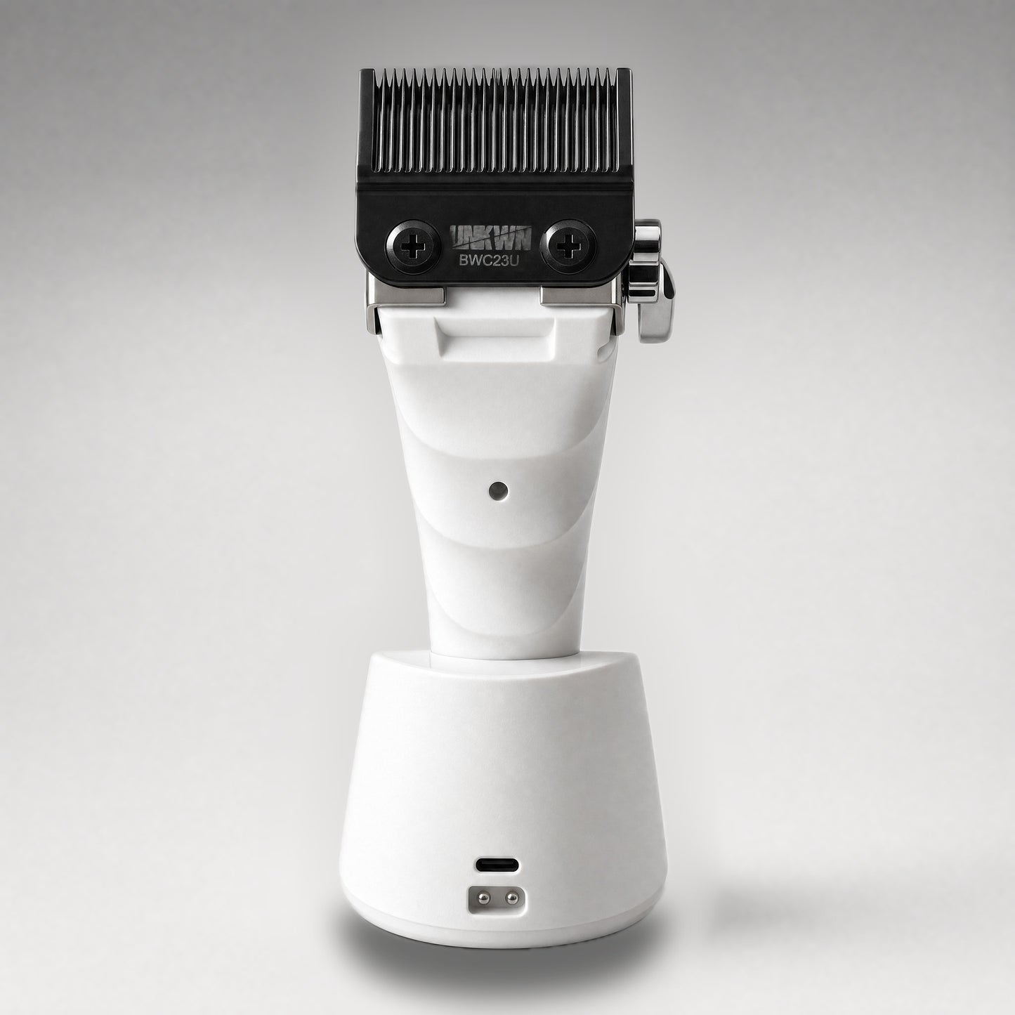 UNKWN Cyclone Clipper UNK1C in white, rear view in the charging dock showing the USB-C port and charging contacts