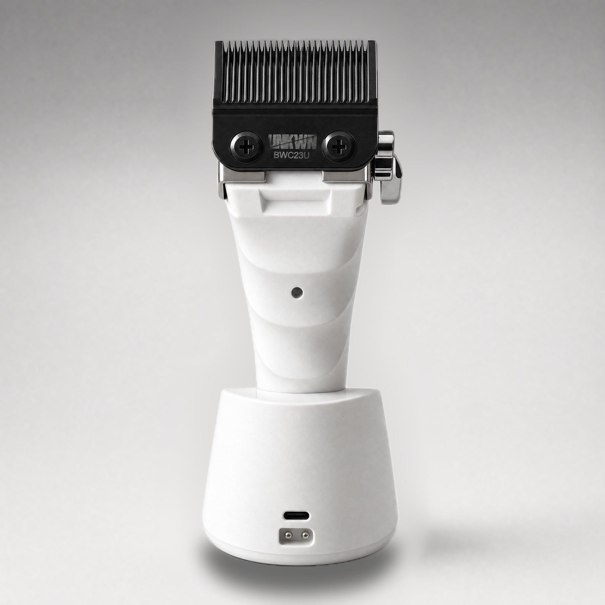 UNKWN Cyclone Clipper UNK1C in white, rear view in the charging dock showing the USB-C port and charging contacts