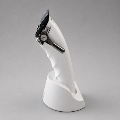 Three-quarter front view of the white UNKWN Vortex Cyclone Clipper in its charging dock, showing the blade, taper lever and brushless motor window